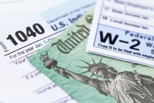 A pile of US tax forms, like a 1040 and W-2, that must be completed to receive your tax refund.