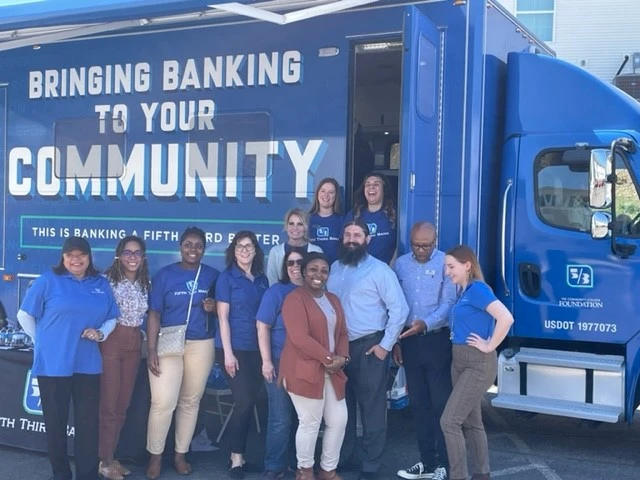 A group of Fifth Third volunteers stand in front of the the e-bus.