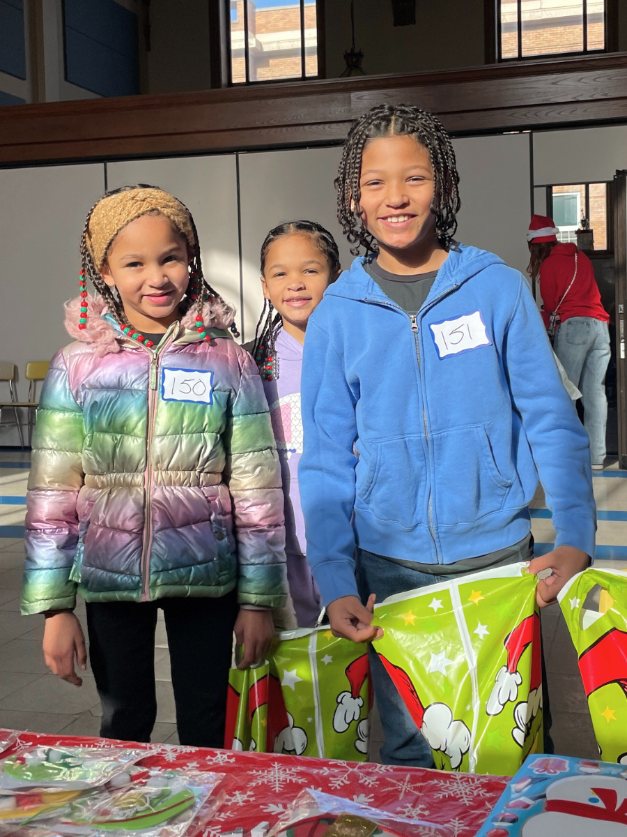 Three children smiling at the 2024 Santa's Workshop, part of WIN's Youth Enrichment Program.